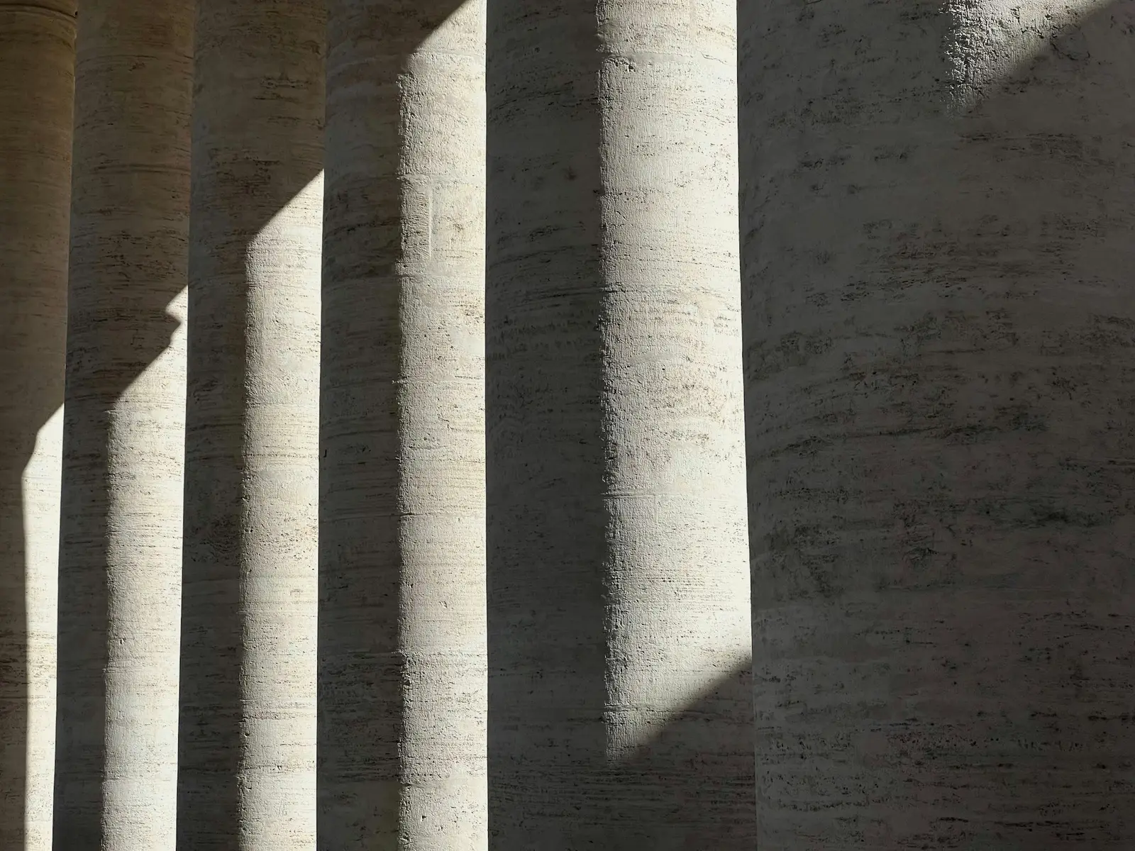 Row of cut stone columns casting strong shadows